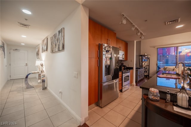 kitchen with wood walls, sink, light tile patterned floors, and stainless steel appliances