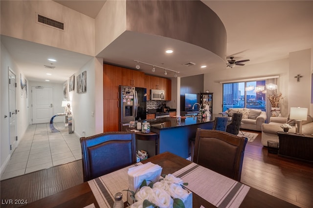 dining space featuring light wood-type flooring, ceiling fan, track lighting, and sink