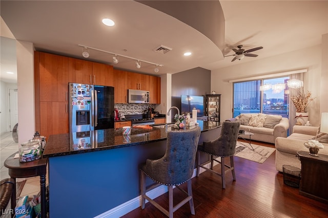 kitchen featuring ceiling fan, sink, appliances with stainless steel finishes, dark hardwood / wood-style floors, and a kitchen breakfast bar