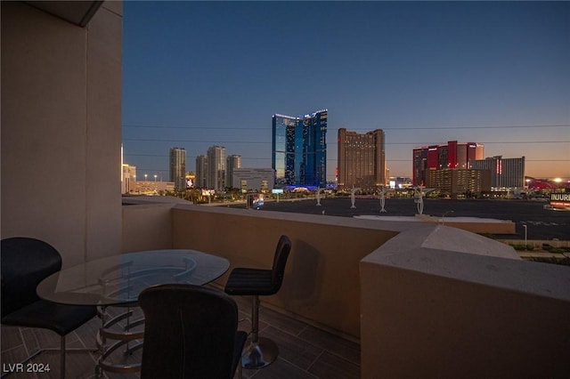 balcony at dusk featuring a view of skyline