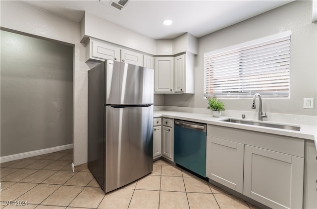 kitchen with appliances with stainless steel finishes, light tile patterned floors, gray cabinetry, and sink