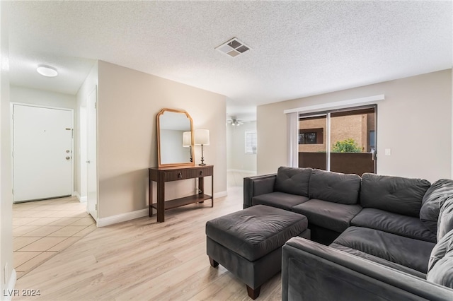 living room featuring ceiling fan, light wood-type flooring, and a textured ceiling