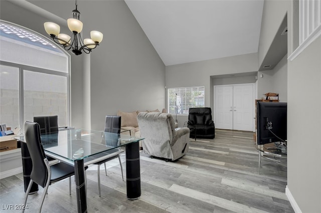 dining space featuring wood-type flooring, an inviting chandelier, and high vaulted ceiling