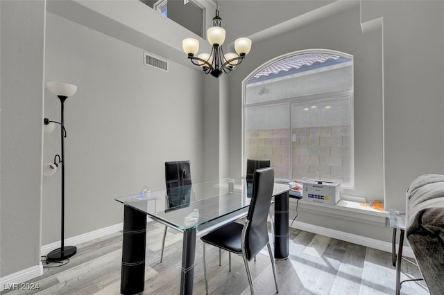 dining room with light wood-type flooring and a chandelier