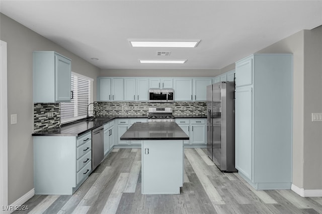 kitchen featuring sink, a kitchen island, light hardwood / wood-style flooring, appliances with stainless steel finishes, and decorative backsplash