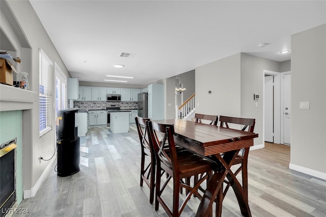 dining space with a notable chandelier and light hardwood / wood-style floors