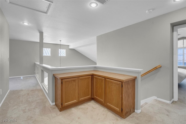 hallway with light carpet, lofted ceiling, and plenty of natural light