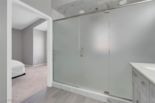 bathroom featuring wood-type flooring, a shower with shower door, and vanity