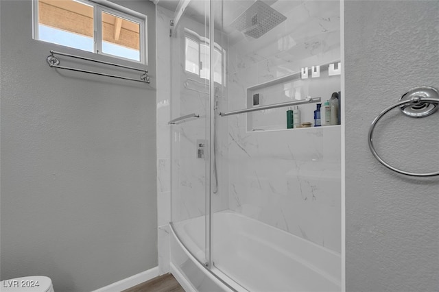 bathroom with enclosed tub / shower combo and toilet