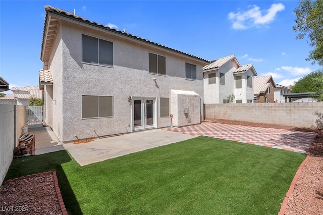 back of house with a lawn and a patio