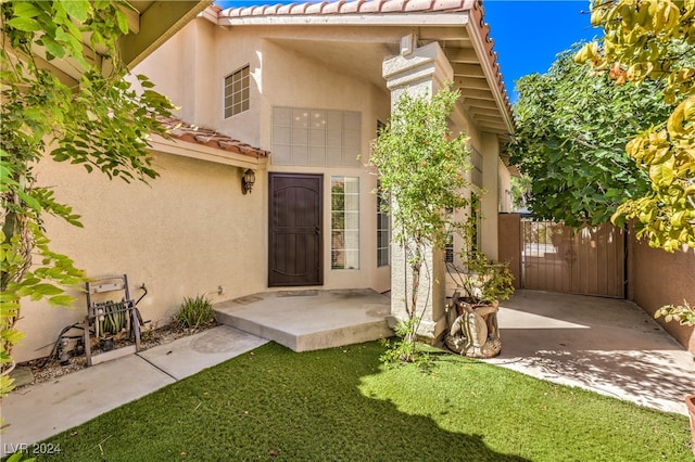 doorway to property featuring a lawn and a patio