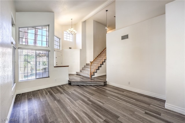 unfurnished living room with a chandelier, dark wood-type flooring, and high vaulted ceiling