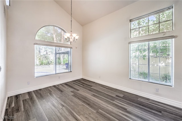 spare room with high vaulted ceiling, a wealth of natural light, a notable chandelier, and dark hardwood / wood-style flooring