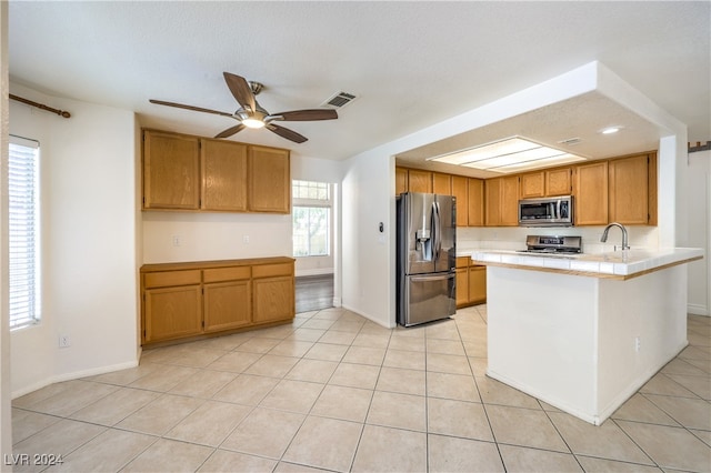 kitchen featuring light tile patterned floors, stainless steel appliances, ceiling fan, and a healthy amount of sunlight