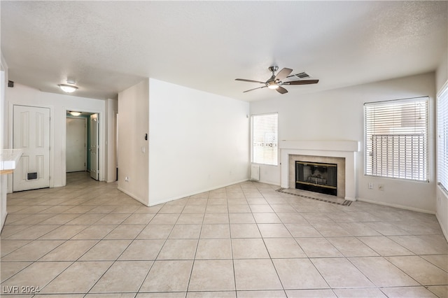 unfurnished living room with a textured ceiling, light tile patterned floors, and ceiling fan