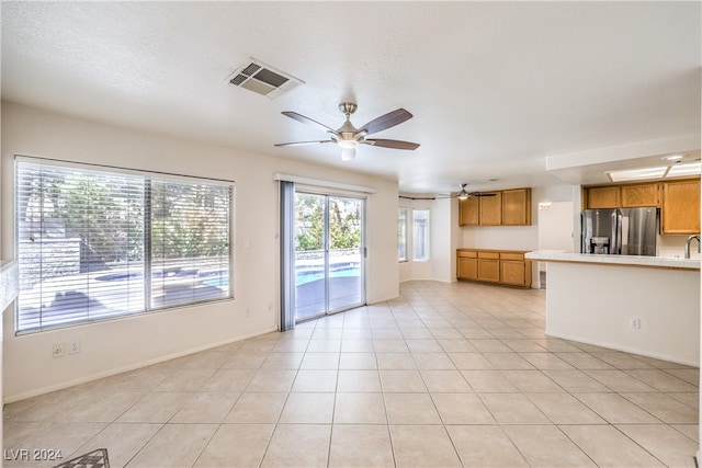 unfurnished living room with ceiling fan, light tile patterned flooring, and a textured ceiling