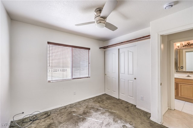 unfurnished bedroom featuring ceiling fan, a textured ceiling, ensuite bath, and sink