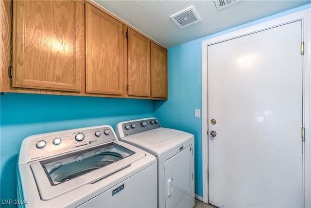 laundry area with cabinets, a textured ceiling, and separate washer and dryer