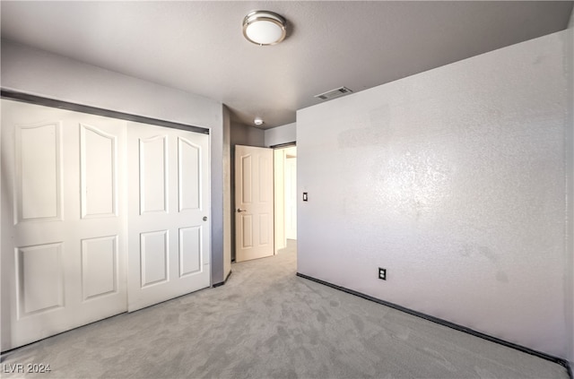 unfurnished bedroom featuring light carpet and a closet