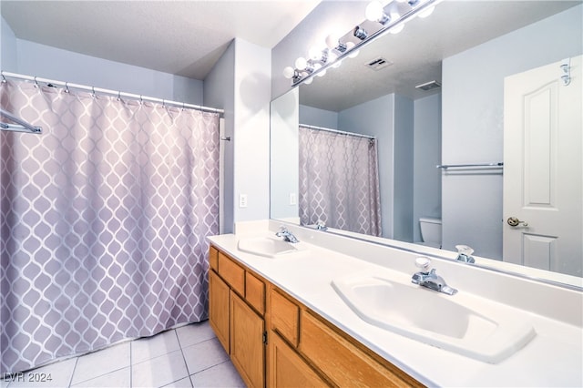 bathroom with curtained shower, vanity, a textured ceiling, toilet, and tile patterned floors