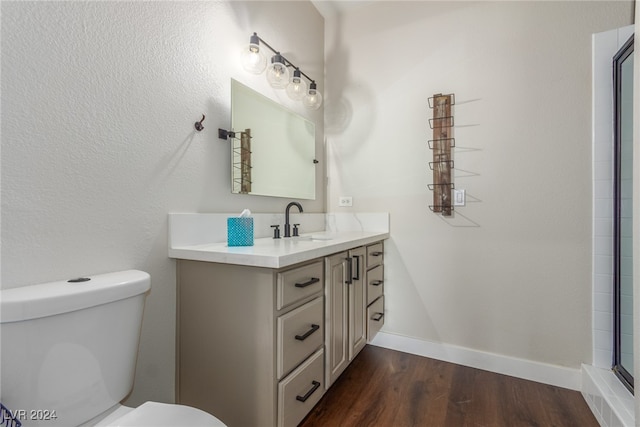 bathroom with vanity, hardwood / wood-style floors, toilet, and a shower with door