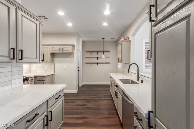 kitchen with light stone counters, sink, decorative light fixtures, dishwasher, and dark hardwood / wood-style floors