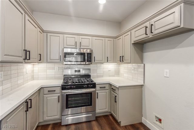 kitchen featuring appliances with stainless steel finishes, decorative backsplash, and dark hardwood / wood-style floors