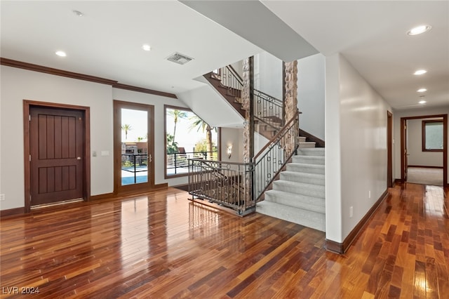 foyer entrance with crown molding and dark hardwood / wood-style flooring