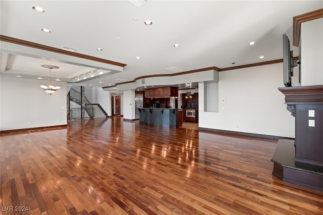 unfurnished living room featuring crown molding, dark hardwood / wood-style floors, and a chandelier