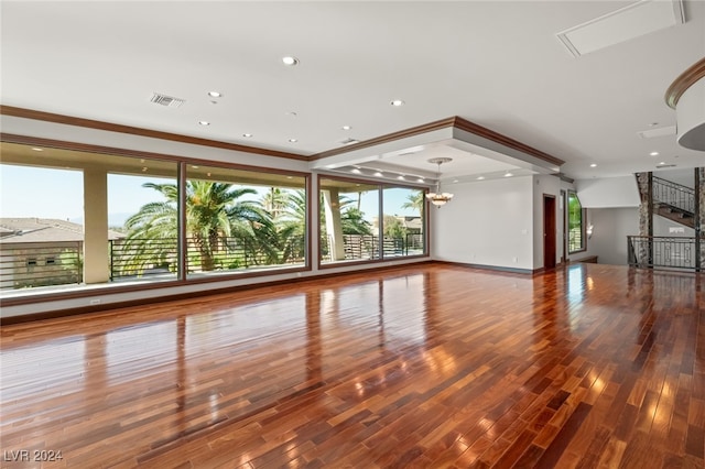 unfurnished living room featuring wood-type flooring, crown molding, and a chandelier