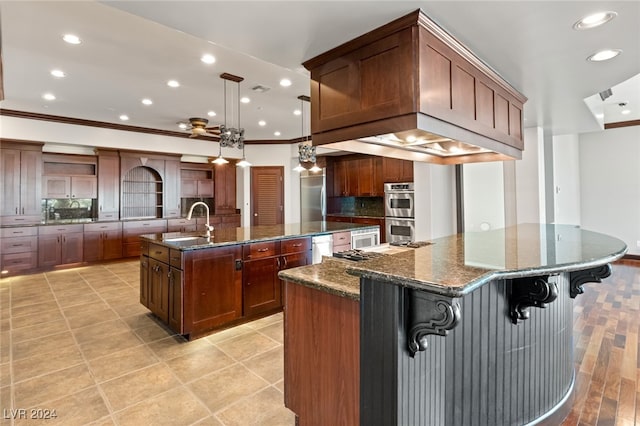 kitchen featuring appliances with stainless steel finishes, a large island with sink, dark stone counters, and decorative backsplash