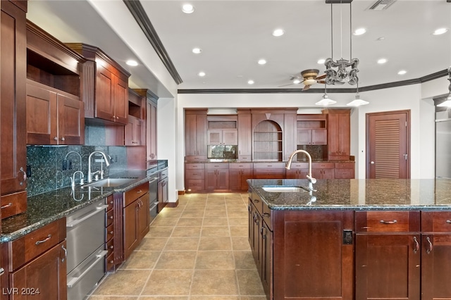 kitchen with decorative light fixtures, a kitchen island with sink, and sink