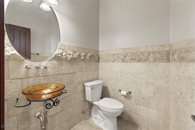 bathroom featuring toilet, sink, backsplash, tile walls, and tile patterned flooring