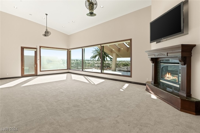 unfurnished living room with carpet, a premium fireplace, and high vaulted ceiling