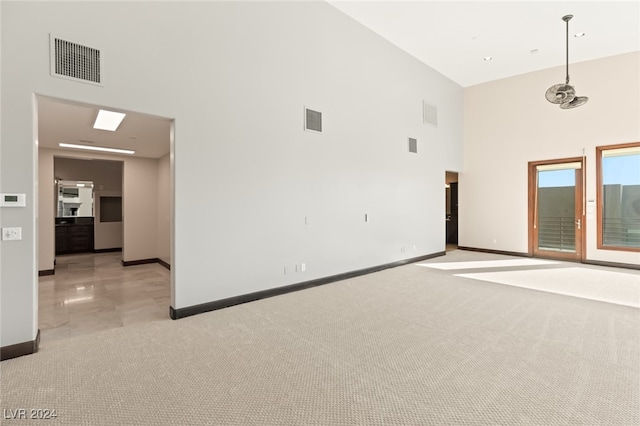 empty room with light colored carpet and a towering ceiling