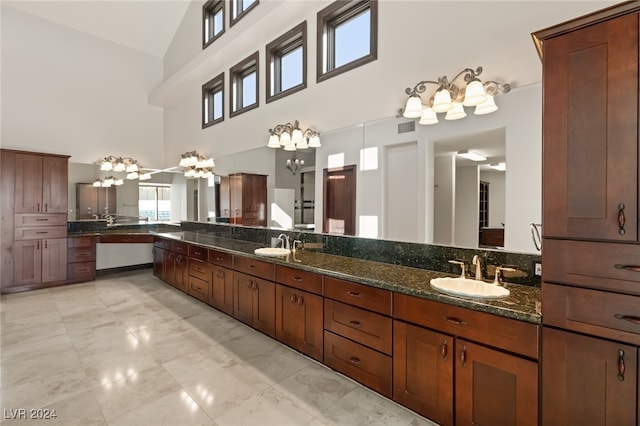 bathroom with high vaulted ceiling, an inviting chandelier, and vanity