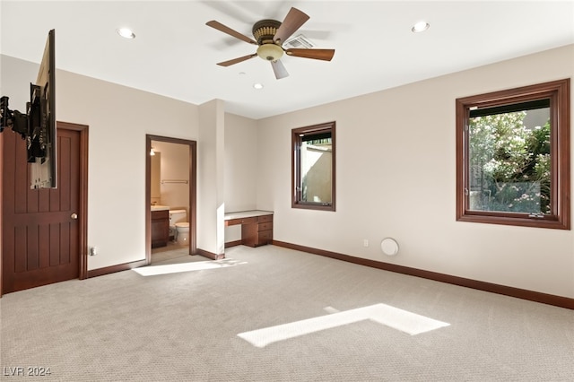 unfurnished bedroom featuring ceiling fan, light colored carpet, and ensuite bathroom