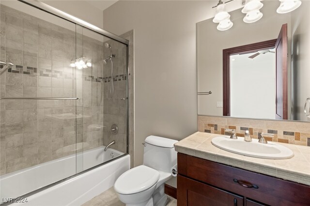 full bathroom featuring backsplash, combined bath / shower with glass door, vanity, and toilet