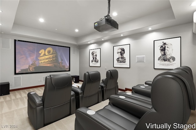 cinema room featuring a tray ceiling and light colored carpet