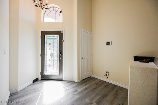 foyer entrance with a notable chandelier, a towering ceiling, and hardwood / wood-style floors