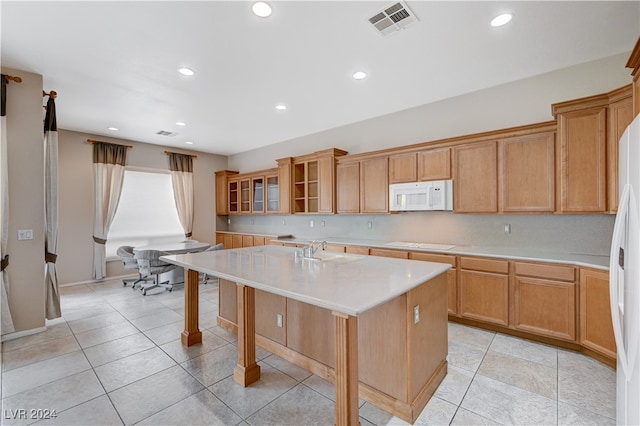 kitchen featuring a center island with sink, white appliances, sink, and light tile patterned floors