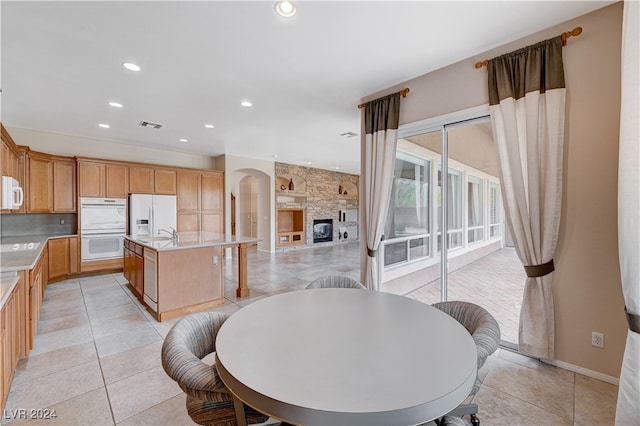 tiled dining area with a stone fireplace and sink