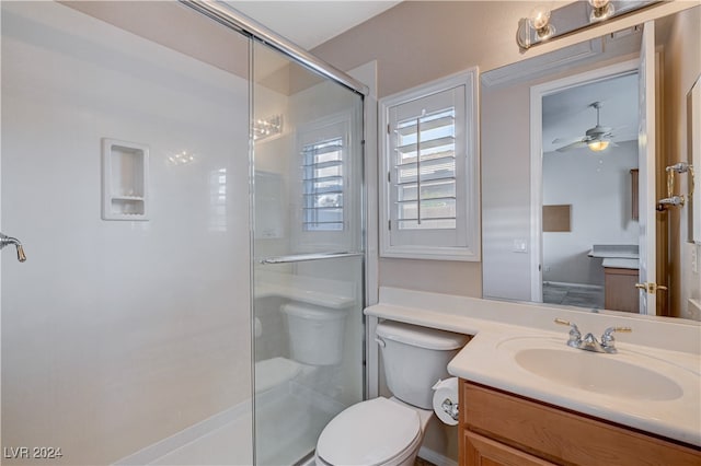 bathroom with ceiling fan, a shower with door, vanity, and toilet