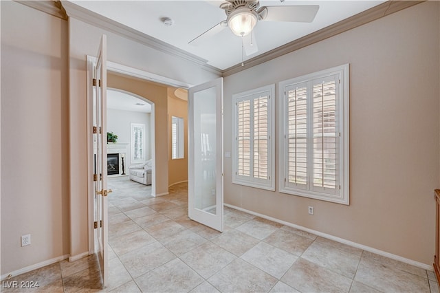 tiled spare room with ornamental molding, a wealth of natural light, and ceiling fan