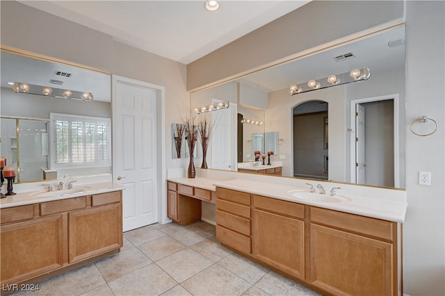 bathroom with a shower with door, vanity, and tile patterned floors