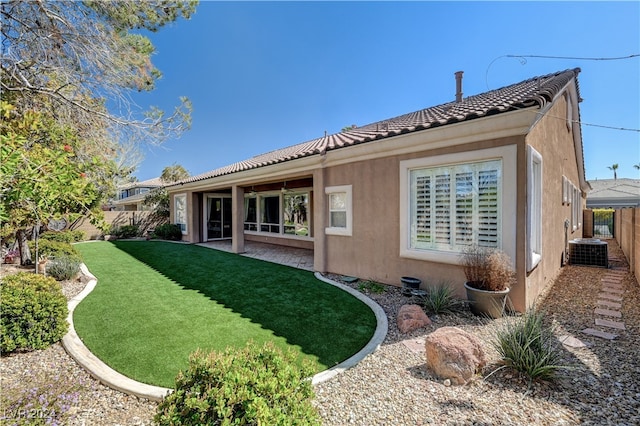 rear view of property featuring a lawn, central AC unit, and a patio area