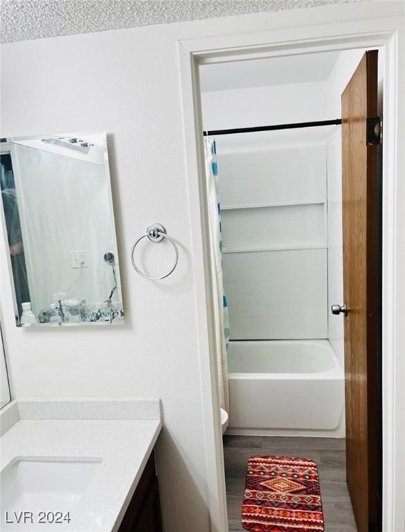 bathroom featuring a textured ceiling, vanity, hardwood / wood-style flooring, and shower / bathtub combination with curtain