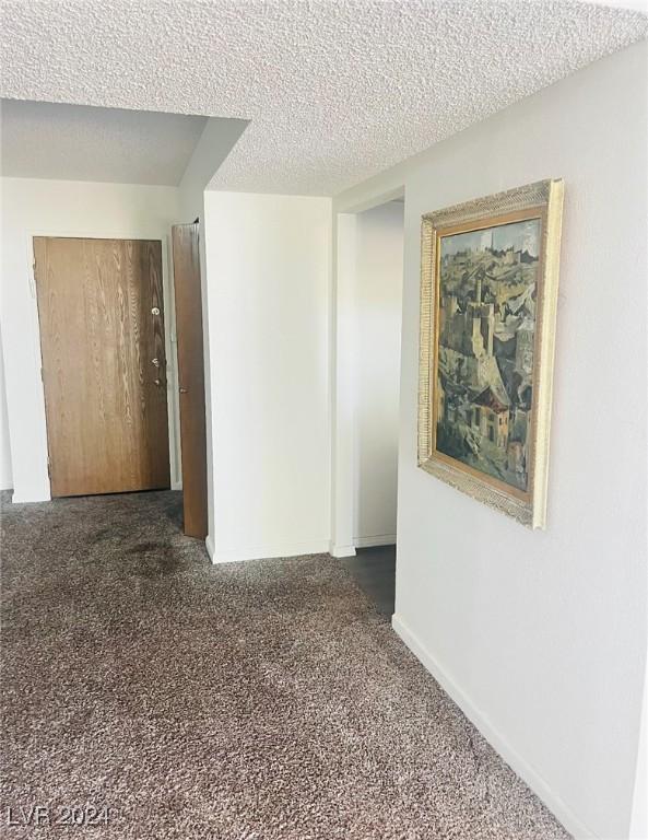 unfurnished room with dark carpet and a textured ceiling