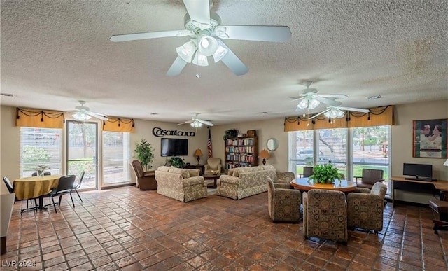 living room featuring ceiling fan, plenty of natural light, and a textured ceiling