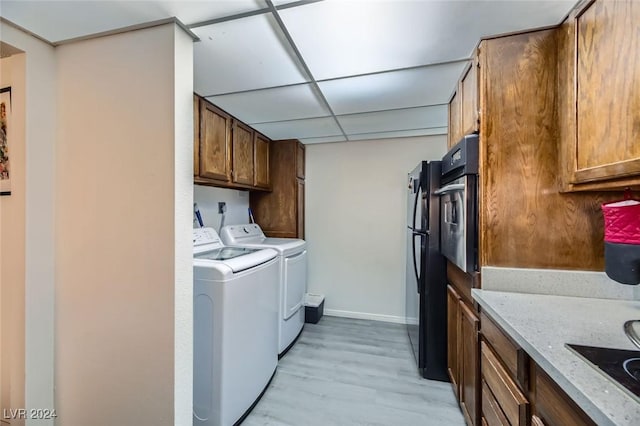 laundry area featuring washer and dryer and light hardwood / wood-style flooring